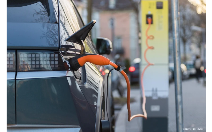 Nahaufnahme eines Ladevorgangs von einem Elektroauto mit einem orangenen Netzstecker.