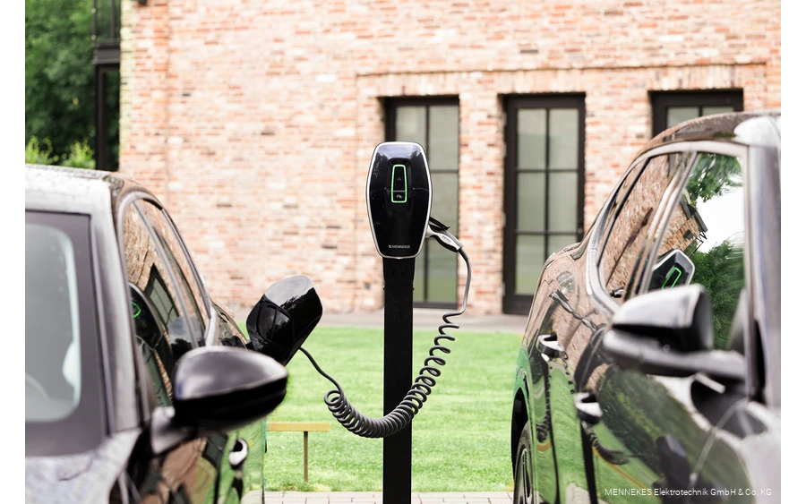 Nahaufnahme eines Ladevorgangs von einem Elektroauto mit einem orangenen Netzstecker.